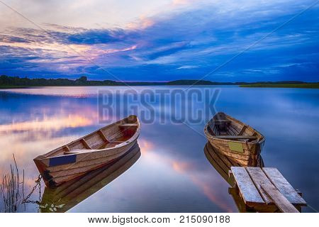 Travel Destinations Concepts. Tranquil and Peaceful Picturesque Landscape of The Strusto Lake with Wooden Boats at Foreground. Lake is a Part of National Braslav Lakes Reserve. Horizontal Image