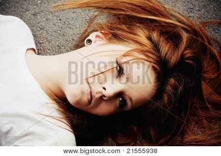 Portrait Of Beautiful Young Girl Lying On Asphalt