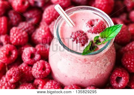 Beautiful appetizer pink raspberries fruit smoothie. Yogurt cocktail. Close up. Natural detox. Liquid ice cream. Glass of raspberry milk shake with berries background, top view.