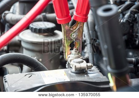 red clamp on car battery. for charging battery car with electricity. selective focus at between red clamp and battery pole