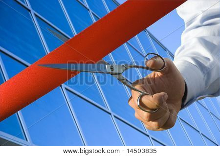 Red ribbon cutting with a pair of scissors for the inauguration of the new business activity