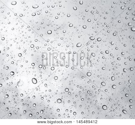 Drops of rain on glass , rain drops on clear window / rain drops with clouds / water drops on glass after rain background / water drops / Small water drops on the glass