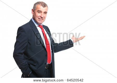 mid aged business man presenting something in the back while holding a hand in his pocket and smiling for the camera. isolated on a white background