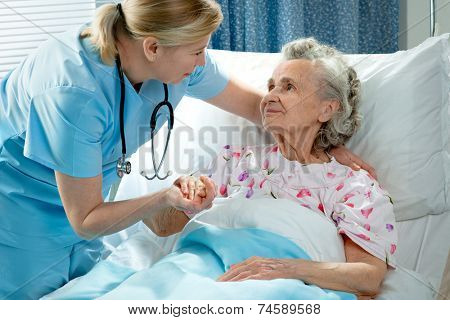 Nurse cares for a elderly woman lying in bed