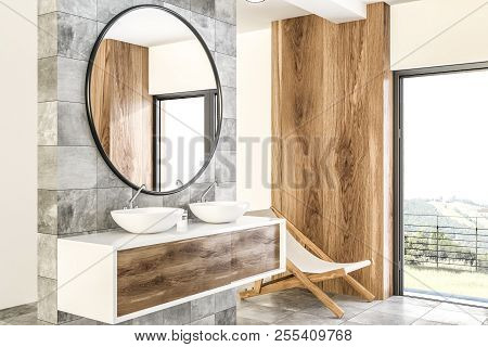 White Double Sink On Wood Counter With A Round Mirror Hanging Above It In A Luxury Marble And Wooden