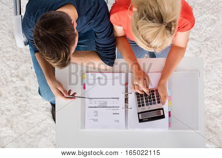 Couple Using Calculator For Calculating Invoice Tax Bills And Retirement Money On Desk At Home