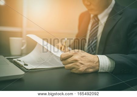 Business man signing a contract . Business man Close-up photo vintage tone Close up of hand of businessman signing a form. Business man signing contract for future deal. Business man signing legal document. Male hand signing employee contract with a bond.