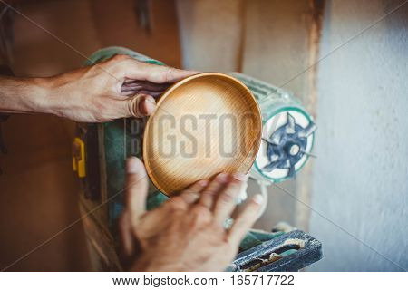 Wood turners using sandpaper polished wood on a lathe