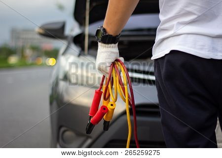 Car Mechanic Man Holding Battery Jumper Cables To Charge A Dead Battery.
Close Up Hand Charging Car 