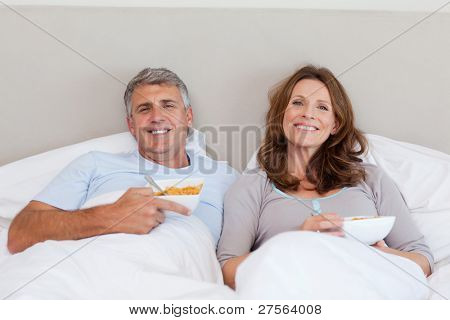 Pareja comer cereales en la cama