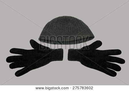 A Pair Of Grey Winter Knitted Gloves And A Grey Winter Hat. On A Gray Background. The View From The 