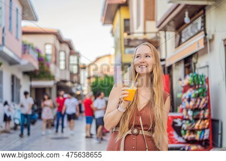 Happy Woman Tourist With Fresh Juice On Background Of Old Street Of Antalya. Female Tourist Traveler