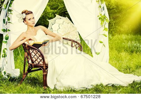 Charming elegant bride under the wedding arch. Wedding dress and accessories. Wedding decoration. 