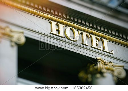 Sun flare above hotel word with golden letters on luxury hotel with beautiful columns