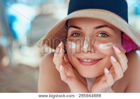 Skincare. Beauty Concept. Young Pretty Woman Applying Sun Cream  And Touch Own Face. Female In Hat S