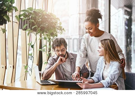 Happy Multiracial Millennial Colleagues Discussing Company Financial Statistics At Briefing In Offic