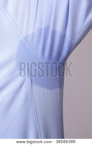 Man with hyperhidrosis sweating very badly under armpit in blue shirt, isolated on grey