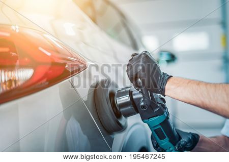 Car detailing - Man holds a polisher in the hand and polishes the car. Selective focus.