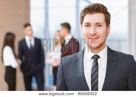 Young business man standing in front of his co-workers  talking