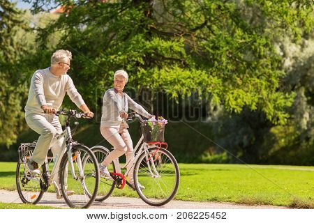 active old age, people and lifestyle concept - happy senior couple riding bicycles at summer park