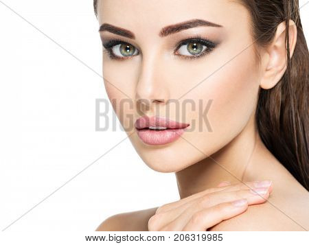 Beauty face of the young beautiful woman - isolated on white. Gorgeous female portrait with slicked brown hair. Young adult girl with healthy skin. Pretty lady with fashion eye makeup. 