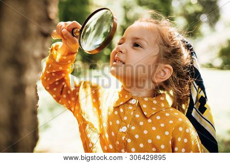 Cute Happy Kid With Magnifying Glass Exploring The Nature Outdoor. Adorable Little Explorer Girl Pla