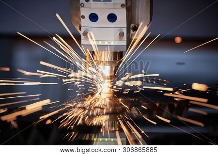 Laser cutting. Metal machining with sparks on CNC laser engraving maching