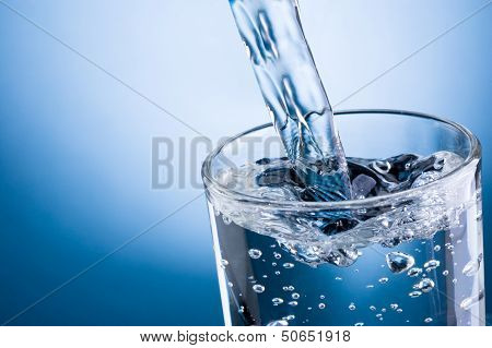 Pouring Water Into Glass On Blue Background