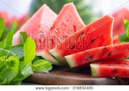 Composition of ripe watermelon and fresh mint on the kitchen table. Ripe summer watermelon. Juicy watermelon. Concept of seasonal fruits on the table