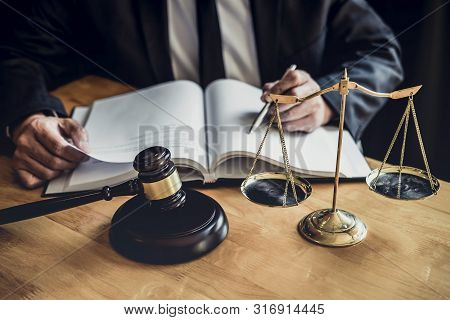 Male Lawyer Or Judge Working With Contract Papers, Law Book And Wooden Gavel On Table In Courtroom, 