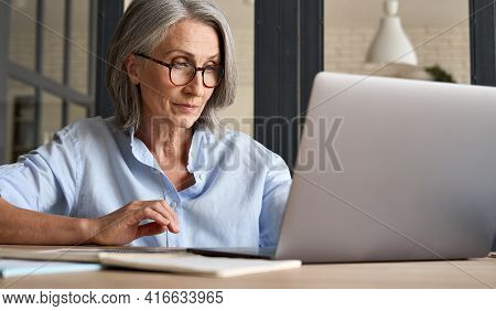 Mature Adult 60s Aged Woman Working At Laptop Watching Video Conference Webinar Training, Virtual Me