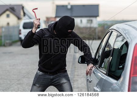 Car Thief Breaking A Glass In Car With Crowbar