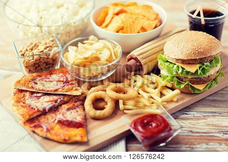 fast food and unhealthy eating concept - close up of fast food snacks and coca cola drink on wooden table