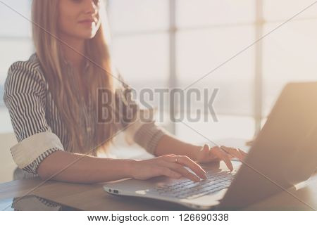 Female writer typing using laptop keyboard at her workplace in the morning. Woman writing blogs online, side view close-up picture