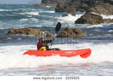 Man Kayaking In The Sea Near Rocks