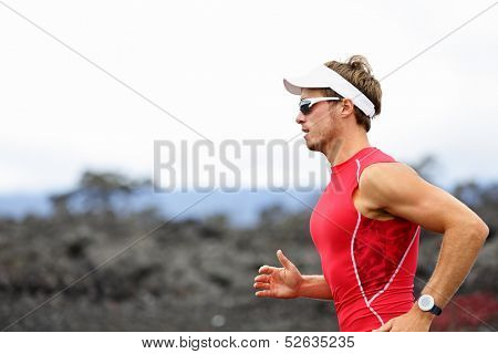 Running triathlon athlete man. Runner triathlete training for ironman on Hawaii. Young Male athlete running in red compression top on volcano in Kailua-Kona, Big Island, Hawaii.