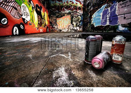 A derelict area of graffiti. Urban setting with empty spray cans neatly positioned to the right.