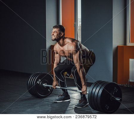 European Caucasian Athletic Man Doing Deadlift With Heavy Barbell. Man Lifting Barbell Opposite Wind