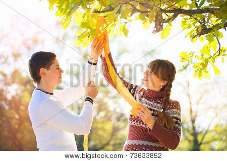 Beautiful Young Pregnant Couple Having Picnic In Autumn Park. Happy Family Outdoor.