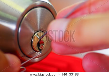 Closeup hands of locksmith using metal pick tools to open locked door.