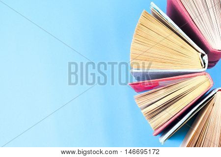 Top view of colorful hardback books in a circle. Open book fanned pages free copy space. Back to school copy space. Education background.