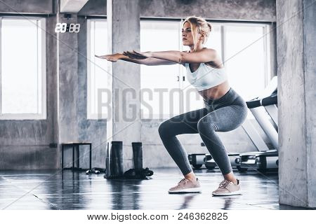 Attractive Young Woman Doing Squat Exercise At The Gym.