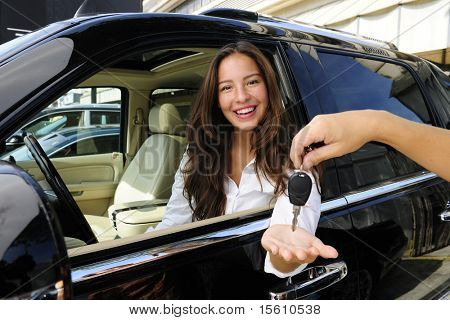 businesswoman receiving keys of her new status car from dealer