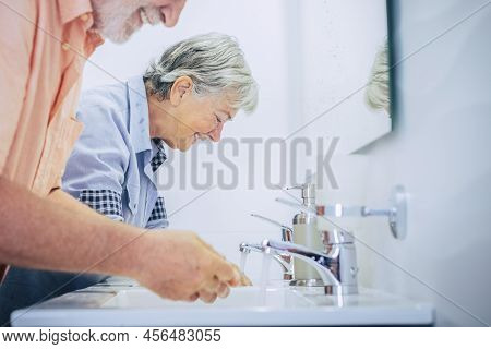 Couple Of Senior Man And Woman Washing Ahnds At Home In The Bathroom In Getting Ready At The Morning