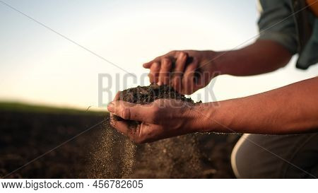 Soil In The Hands Of The Farmer. Agriculture. Close-up Of A Farmers Hands Holding Black Soil In Sun 