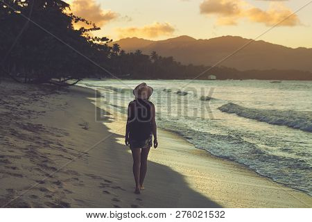 Traveler Girl Walking On Tropical Beach In Sunset. Vintage Photo Of Young Girl Traveler In Vacation.