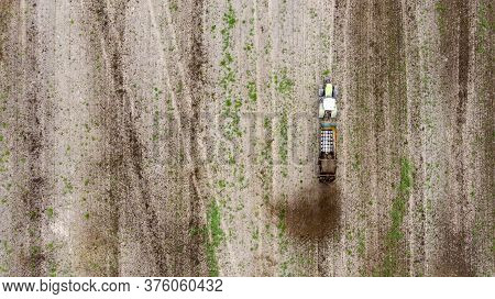 A Tractor With A Trailer Fertilizes The Field With Natural Fertilizer-manure. Aerial View.