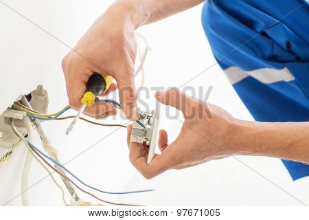 repair, renovation, electricity and people concept - close up of electrician hands with screwdriver fixing socket