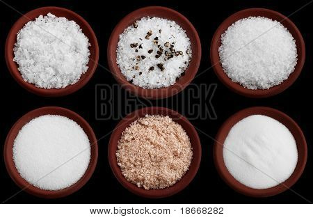 six terracotta plates with different salt - flakes sea salt, coarse sea salt with crashed black pepper, coarse sea salt, fine sea salt, smoked flaky sea salt, table salt, Isolated on black