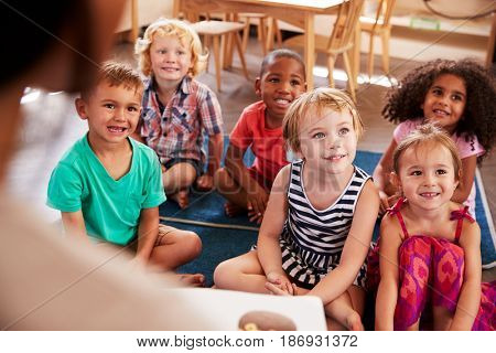 Teacher At Montessori School Reading To Children At Story Time